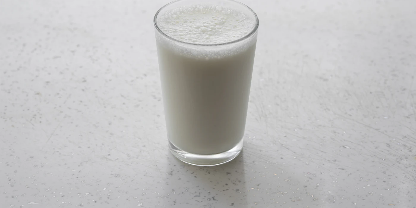 A full glass of milk on a pale speckled countertop