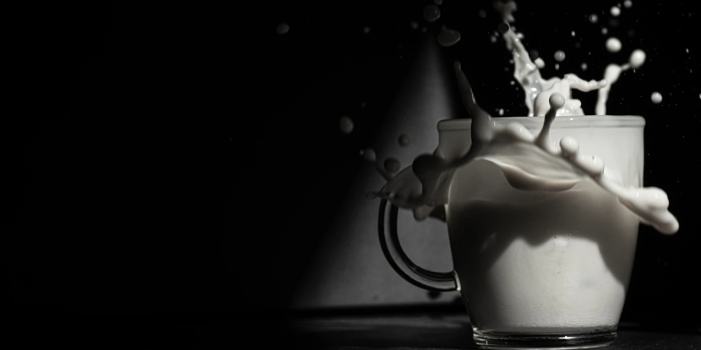 A splash of milk caught mid-motion above a full glass