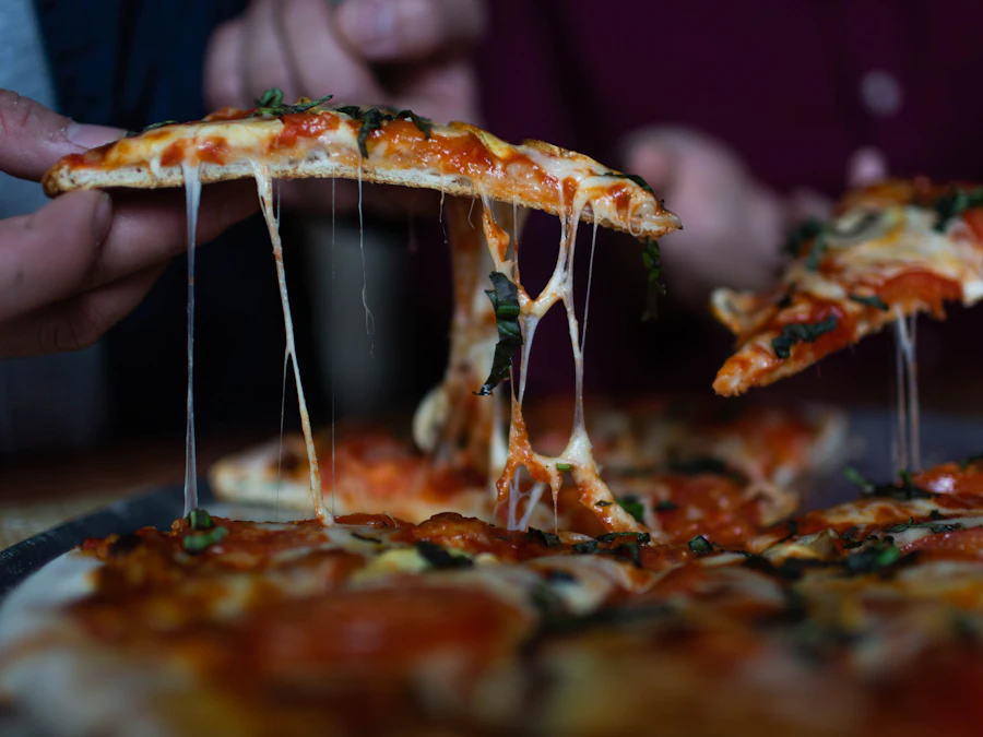 A slice of pizza lifted from the pie, cheese stretching